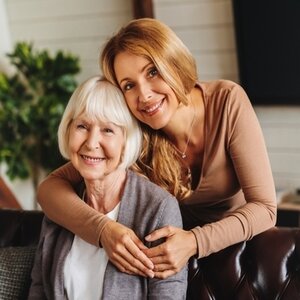 Two females hugging, sitting on a couch.